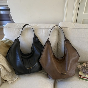 Detail view of large leather Hobo tote bags in black and dark brown on a cozy sofa