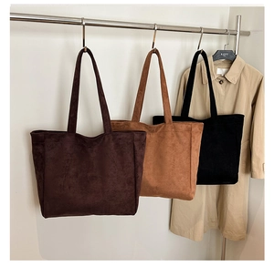 Three minimalist suede tote bags in brown and black colors hanging in a row for work