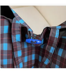 Vue détaillée du cordon de serrage et du curseur bleu sur le grand sac à carreaux