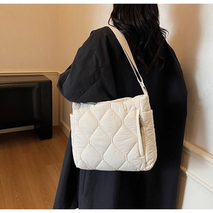 Detailed view of white quilted tote bag with side zipper pocket and wide fabric strap