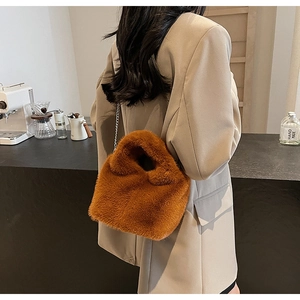 Brown fluffy faux fur bucket bag with silver chain strap shown in a cozy cafe setting