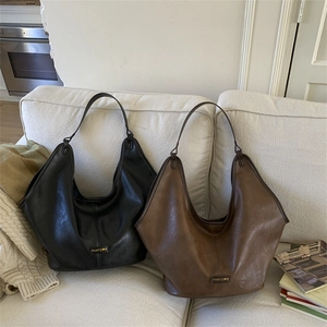 Close-up of large Hobo shoulder bags in brown and black leather on a sofa