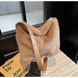 Dettaglio della tracolla in pelle regolabile su una borsa a secchiello in peluche cammello
