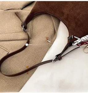 Détail du sac bandoulière en daim marron avec bandoulière en cuir et boucle réglable
