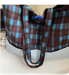 Détail du sac cabas à carreaux avec fermeture à bascule bleue et poches latérales