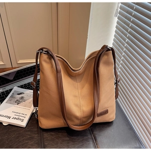 Close-up of khaki canvas tote bag with brown leather straps and brand logo patch