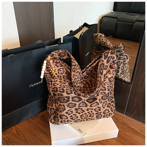 Detail of leopard print tote bag with decorative wooden beads on a display stand