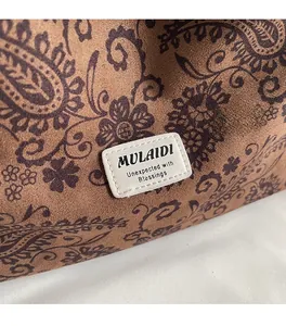 Close-up of brown paisley fabric with a brand label on a stylish shoulder bag