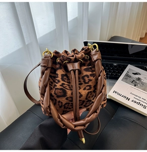 Détail du sac seau à imprimé léopard avec poignée en cuir marron et boucles dorées