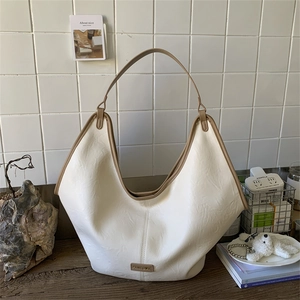 Close-up of cream hobo bag showing pleated faux leather texture and metallic logo plate