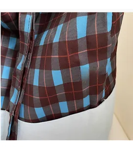 Gros plan sur la texture du tissu à carreaux bleu et marron et les coutures du sac