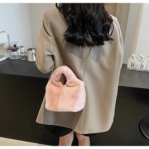 Model wearing a pink faux fur bucket bag with a metal chain strap and soft plush texture