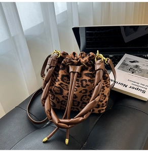Détail du sac seau à motif léopard avec poignée tissée marron et finitions dorées