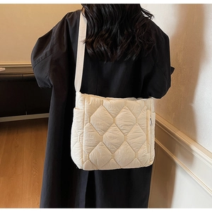 Detail of beige quilted tote bag showing padded texture and canvas shoulder strap