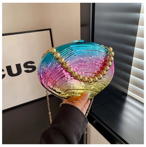 Detail of rainbow gradient shell acrylic evening bag with gold chain strap in hand