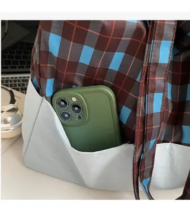 Détail de la poche latérale d'un sac cabas à carreaux contenant un smartphone