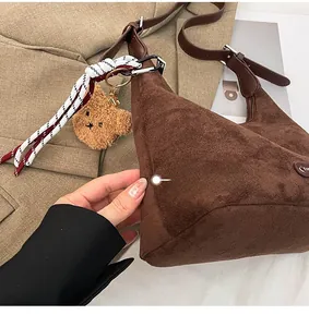 Détail du sac cabas en daim montrant la texture mate, le charm ours et la bandoulière