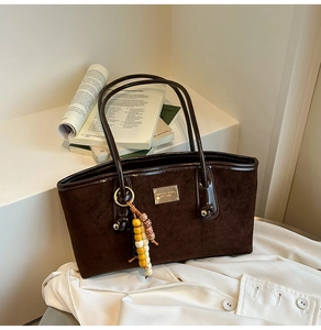 Detail of dark coffee tote bag with suede texture, beaded tassel and gold nameplate