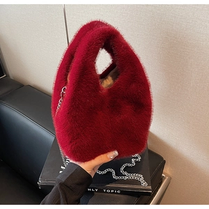 Detail of dark red plush bucket bag showing soft faux fur texture and silver chain strap