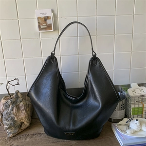Detail shot of the black leather hobo bag's soft texture and metal brand logo