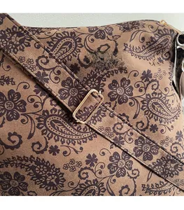 Detail of adjustable shoulder strap with gold metal buckle on brown paisley canvas bag