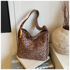 Detail view of leopard print canvas tote bag with wooden bead charm and wide shoulder strap
