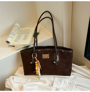 Detail of dark brown suede tote bag with double straps and beaded tassel accent
