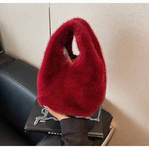 Close-up of bright red faux fur bucket bag featuring a sleek silver metal chain strap
