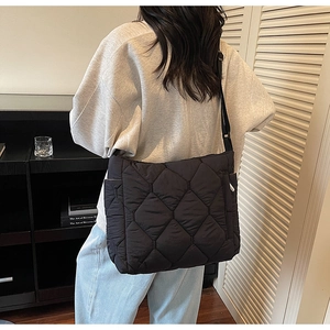 Detail view of large black quilted tote bag with side pocket and adjustable strap