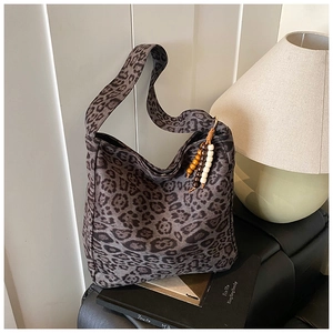 Close-up of leopard print shoulder bag with decorative wooden beads on a leather surface
