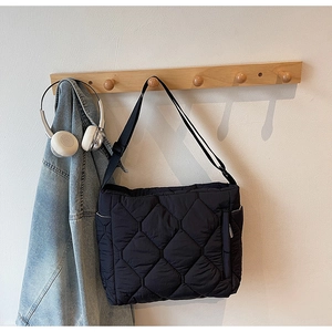 Detail of black quilted puffer tote bag with adjustable strap and side zipper pocket