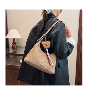 Détail du sac hobo en cuir mat marron avec breloque ours et logo en métal argenté