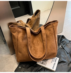 Macro detail of brown suede tote bag featuring a soft matte texture and durable double straps