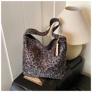 Close-up of leopard print tote bag with wooden bead charm on a book-themed setting