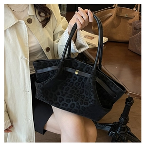 Détail du sac cabas léopard avec anses en cuir noir et boucles métalliques dorées