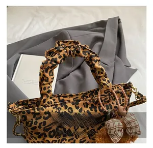Close-up of leopard print bucket bag featuring ruched handles and a cute bear charm