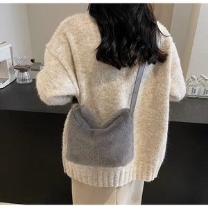Dettaglio borsa a secchiello in ecopelliccia grigia con tracolla su maglia beige