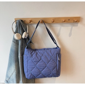 Detail of blue quilted tote bag showing rhombus pattern stitching and side pocket design