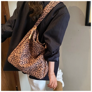 Detail of leopard print tote bag with wooden bead charm and hobo silhouette