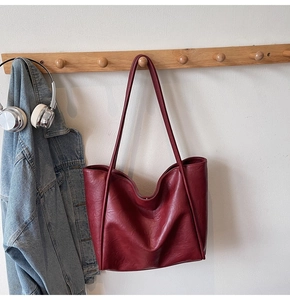 Detail view of burgundy tote bag texture with long straps and large capacity