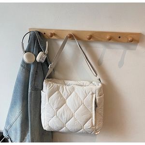 Detail of off-white quilted tote bag with side zipper pocket and adjustable strap