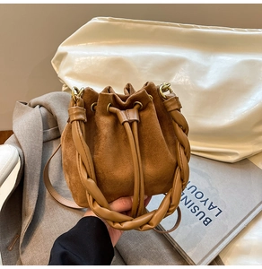Détail du sac seau en daim caramel avec poignée tressée et fermeture à cordon