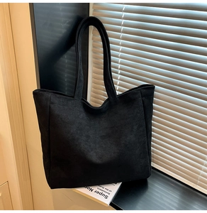 Detailed view of large black tote bag with soft matte texture and long shoulder straps
