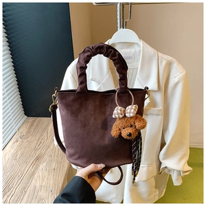 Detail of vintage brown suede bucket bag with ruched handle and teddy bear charm accessory