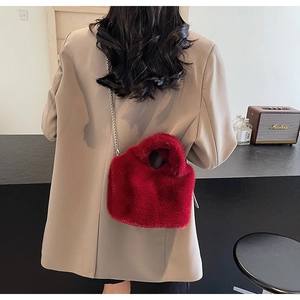 Detailed view of red faux fur bucket bag with silver metal chain on a model back