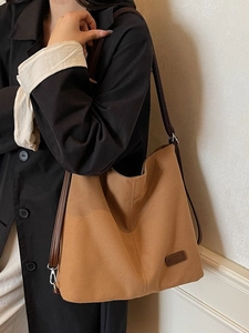 Brown canvas tote bag with adjustable strap shown on a model for daily commute use