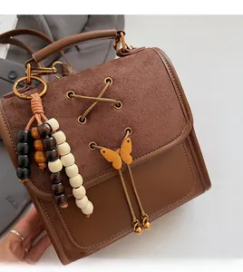 Detail of brown vintage crossbody bag with butterfly clasp and wooden bead tassel