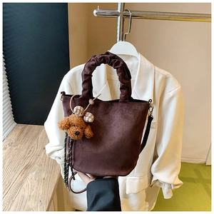 Detail of dark brown matte leather bucket bag with pleated handle and plush puppy charm