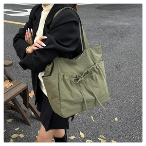 Detail view of large army green canvas tote bag with drawstring pocket and fashion label
