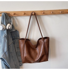 Detailed close-up of large caramel brown leather tote bag with textured surface
